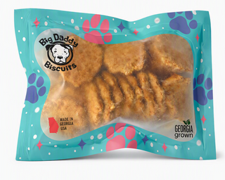 A packaged pet treat product labeled Big Daddy Biscuits, showing several golden-brown biscuit-shaped treats visible through a clear window in a turquoise printed bag with paw-print graphics and 'Made in Georgia USA' text.